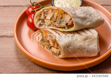 Grilled chicken shawarma or doner with tomatoes, cucumber, and sauces, takeout food Grilled chicken shawarma or doner with tomatoes, cucumber, and sauces, takeout food 141583560