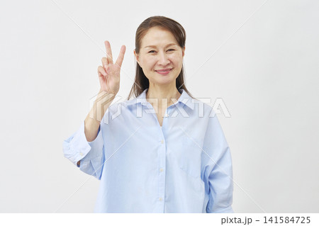 白背景でピースサインをする女性 141584725
