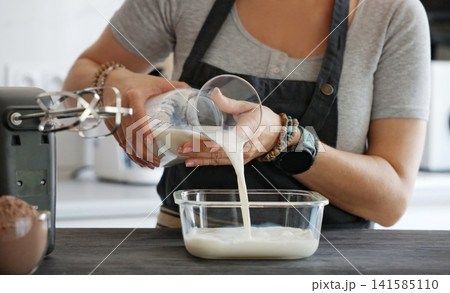 Woman Pouring Milk From A Jar Into A Glass Bowl Cooking In The Kitchen Woman Pouring Milk From A Jar Into A Glass Bowl Cooking In The Kitchen 141585110