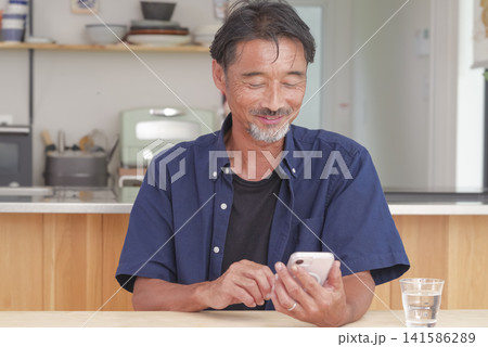 明るい室内でスマホを操作するシニア男性 141586289