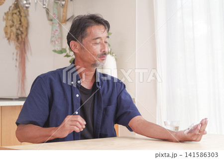 明るい室内でスマホを操作するシニア男性 141586303