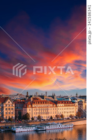 Vltava riverbank and historic buildings under colorful sunset 141586341