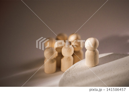 Wooden figurines of diverse shapes and sizes arranged in a group with one figure standing apart on a light surface, showcasing contrast and individuality in design Wooden figurines of diverse shapes and sizes arranged in a group with one figure standing apart on a light surface, showcasing contrast and individuality in design 141586457