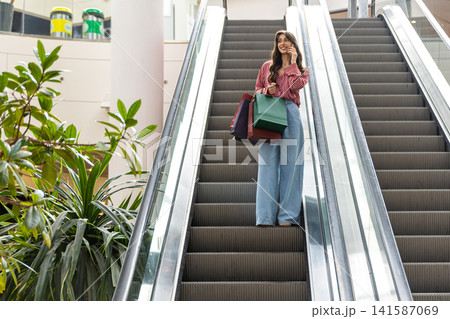 Young woman in the shopping mall with a phone in hands Young woman in the shopping mall with a phone in hands 141587069