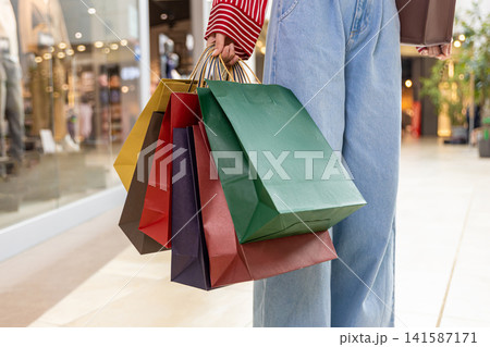 Close up of a woman walking in a shopping center with paper bags in hands 141587171