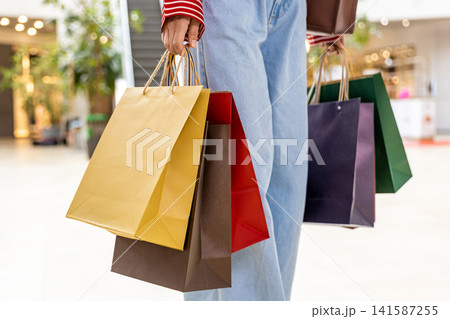 Close up picture of a woman carrying paper shopping bags Close up picture of a woman carrying paper shopping bags 141587255