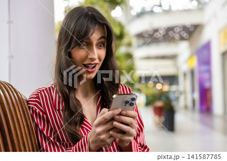 Cute young woman texting on the phone and looking excited 141587785