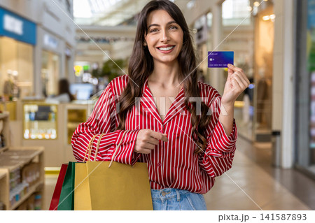 Smiling young woman holding a credit card in hands Smiling young woman holding a credit card in hands 141587893
