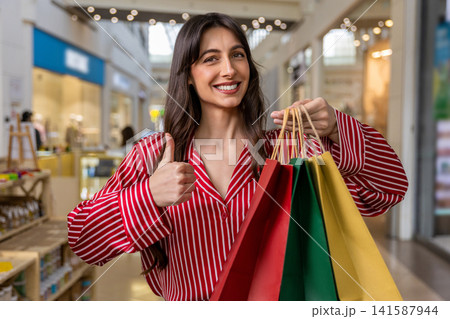Young woman in a red shirt feeling happy and excited after shopping 141587944