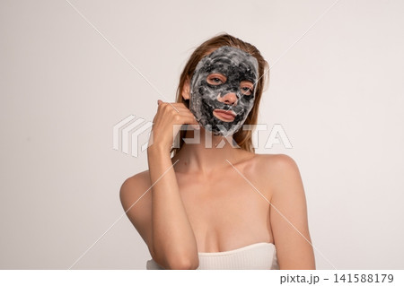 Woman applying bubbling charcoal face mask for skincare routine, cleansing and detoxifying skin, beauty treatment concept Woman applying bubbling charcoal face mask for skincare routine, cleansing and detoxifying skin, beauty treatment concept 141588179