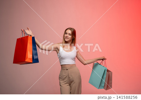 Smiling young woman holding colorful shopping bags expressing happiness and retail consumerism on sale 141588256