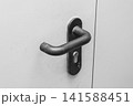 Steel doorknob opening or closing the entrance or exit of the house, close-up 141588451