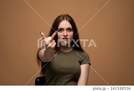 Young woman showing middle finger gesture with angry expression, conveying defiance and frustration Young woman showing middle finger gesture with angry expression, conveying defiance and frustration 141588556