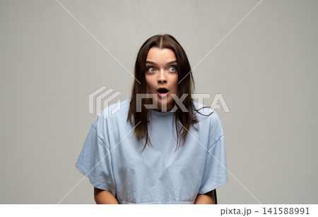 Young woman with wide-eyed surprise, expressing shock and disbelief, mouth open reacting to unexpected news 141588991