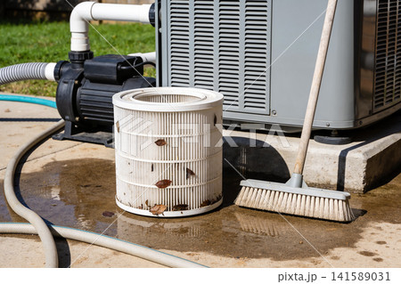 Dirty pool filter and pump with broom on wet concrete during maintenance Dirty pool filter and pump with broom on wet concrete during maintenance 141589031