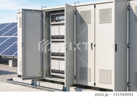 Outdoor electrical cabinet with open door showing internal components and solar panels Outdoor electrical cabinet with open door showing internal components and solar panels 141589091