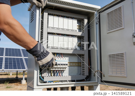 Technician inspecting electrical control panel near solar energy farm 141589121