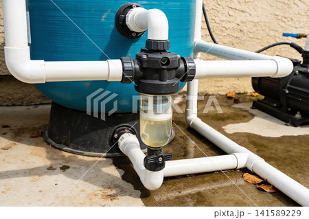 Close-up of a pool pump and filter system with PVC piping and water Close-up of a pool pump and filter system with PVC piping and water 141589229