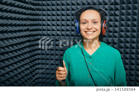 Portrait adult woman while hearing check-up at soundproof audiometric cabin using audiometry headphones and audiometer 141589384