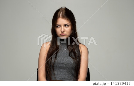 Young woman expressing disinterest and disappointment, looking away with a sullen face and pouty lips 141589415