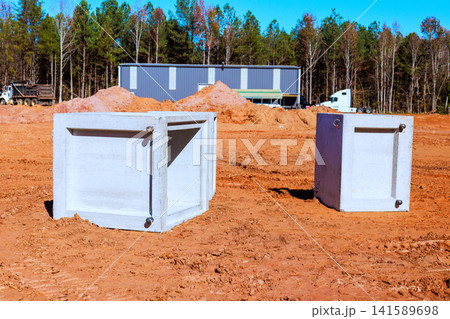 Two concrete waste tank are placed on ground of construction site near forest. Two concrete waste tank are placed on ground of construction site near forest. 141589698