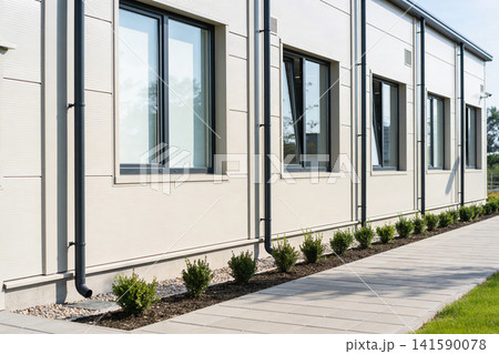 Modern beige building exterior with clean windows and a paved walkway Modern beige building exterior with clean windows and a paved walkway 141590078