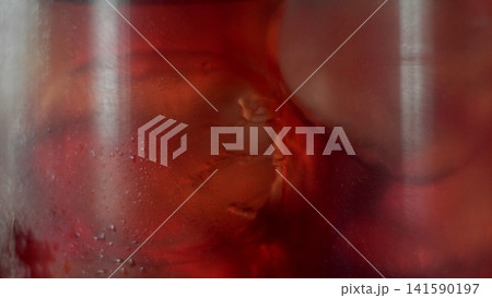 Condensing glass with refreshing red liquid and ice, creating an abstract background texture Condensing glass with refreshing red liquid and ice, creating an abstract background texture 141590197