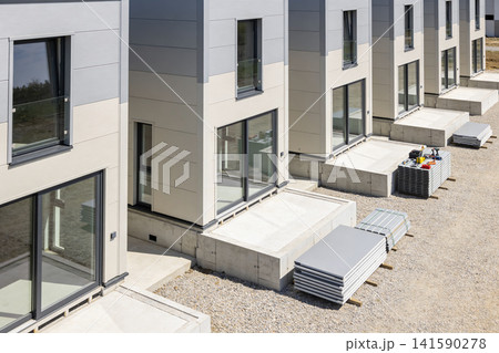 Modern modular houses under construction with building materials on site Modern modular houses under construction with building materials on site 141590278