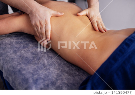 Male therapist providing a relaxing massage to a client on a treatment table, showcasing professional techniques and a serene atmosphere in a wellness environment 141590477