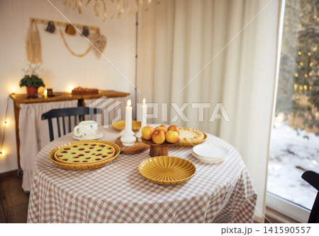 Cozy dining table set with delicious baked goods, fresh apples, and candles, creating a warm atmosphere for gatherings and celebrations in a rustic home setting Cozy dining table set with delicious baked goods, fresh apples, and candles, creating a warm atmosphere for gatherings and celebrations in a rustic home setting 141590557