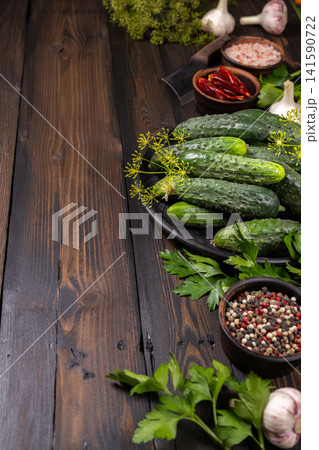 Pickling cucumbers and fresh spices on wooden background Pickling cucumbers and fresh spices on wooden background 141590722