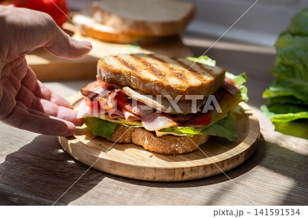 Hand picking up freshly made club sandwich 141591534