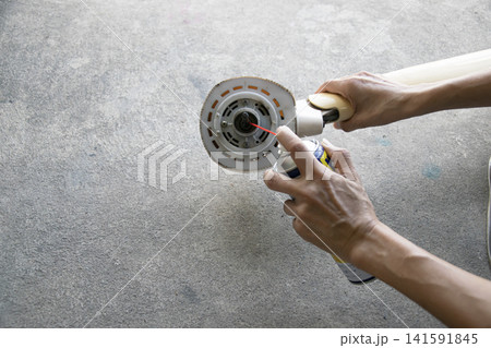 The technician is spraying lubricant on the fan motor. 141591845