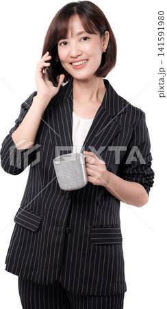 Smiling asian woman engaged in phone conversation, holding beverage mug, radiating happiness and confidence 141591980