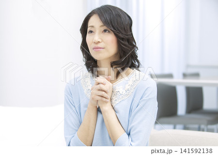 手を合わせて祈る中年女性 141592138