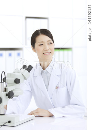 顕微鏡を見る白衣の女性 顕微鏡を見る白衣の女性 141592183