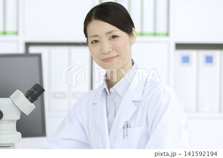 顕微鏡を見る白衣の女性 顕微鏡を見る白衣の女性 141592194