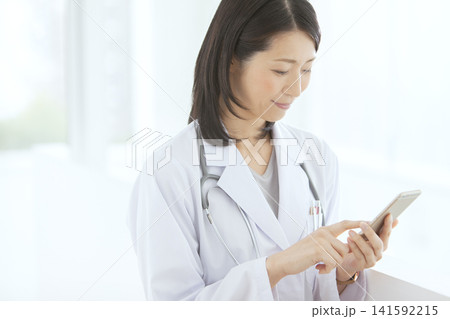 スマートフォンを操作する女性医師 141592215