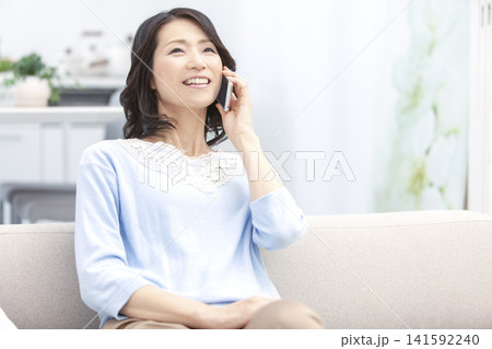 スマートフォンで電話する中年女性 スマートフォンで電話する中年女性 141592240