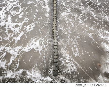 Waves wash over the vertical line of coastal breakwaters 141592657