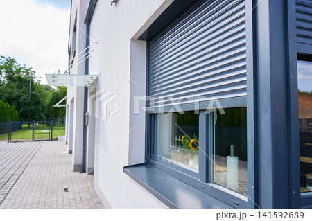 Roller shutter partly covers window on the exterior of modern house Roller shutter partly covers window on the exterior of modern house 141592689