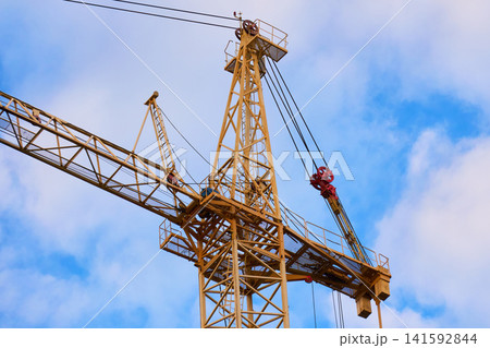 Lattice structure of a yellow tower crane against cloudy sky Lattice structure of a yellow tower crane against cloudy sky 141592844