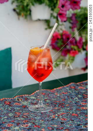 Red aperitif with ice and orange on a cafe table. Concept of relaxation, travel, refreshment, summer, lifestyle. Aperol Spritz and Campari Spritz Red aperitif with ice and orange on a cafe table. Concept of relaxation, travel, refreshment, summer, lifestyle. Aperol Spritz and Campari Spritz 141593003