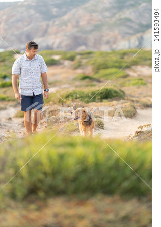 Man and airedale terrier walking on coastal path 141593494