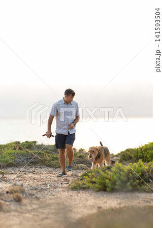 Man walking dog on path enjoying nature Man walking dog on path enjoying nature 141593504