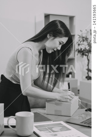 Startup SME small business entrepreneur of freelance Asian woman wearing apron using laptop and box to receive and review orders online to prepare to pack sell to customers, online sme business ideas. Startup SME small business entrepreneur of freelance Asian woman wearing apron using laptop and box to receive and review orders online to prepare to pack sell to customers, online sme business ideas. 141593665