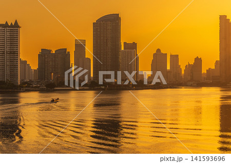 Golden hour cityscape with river and boat at sunrise Golden hour cityscape with river and boat at sunrise 141593696