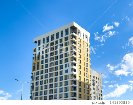 Modern residential apartment building with blue sky and clouds in urban setting Modern residential apartment building with blue sky and clouds in urban setting 141593839
