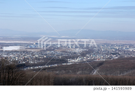 Winter aerial view of Arsenyev city from mountain top. Snow-covered houses and buildings in Far East Russian town. Panoramic cityscape with winter landscape Winter aerial view of Arsenyev city from mountain top. Snow-covered houses and buildings in Far East Russian town. Panoramic cityscape with winter landscape 141593989