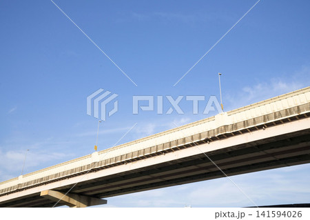 晴れ渡った青空を背景にそびえ立つ高速道路の高架橋と橋脚のローアングル景観 晴れ渡った青空を背景にそびえ立つ高速道路の高架橋と橋脚のローアングル景観 141594026